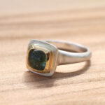 Silberring mit grünem Stein in goldener Fassung